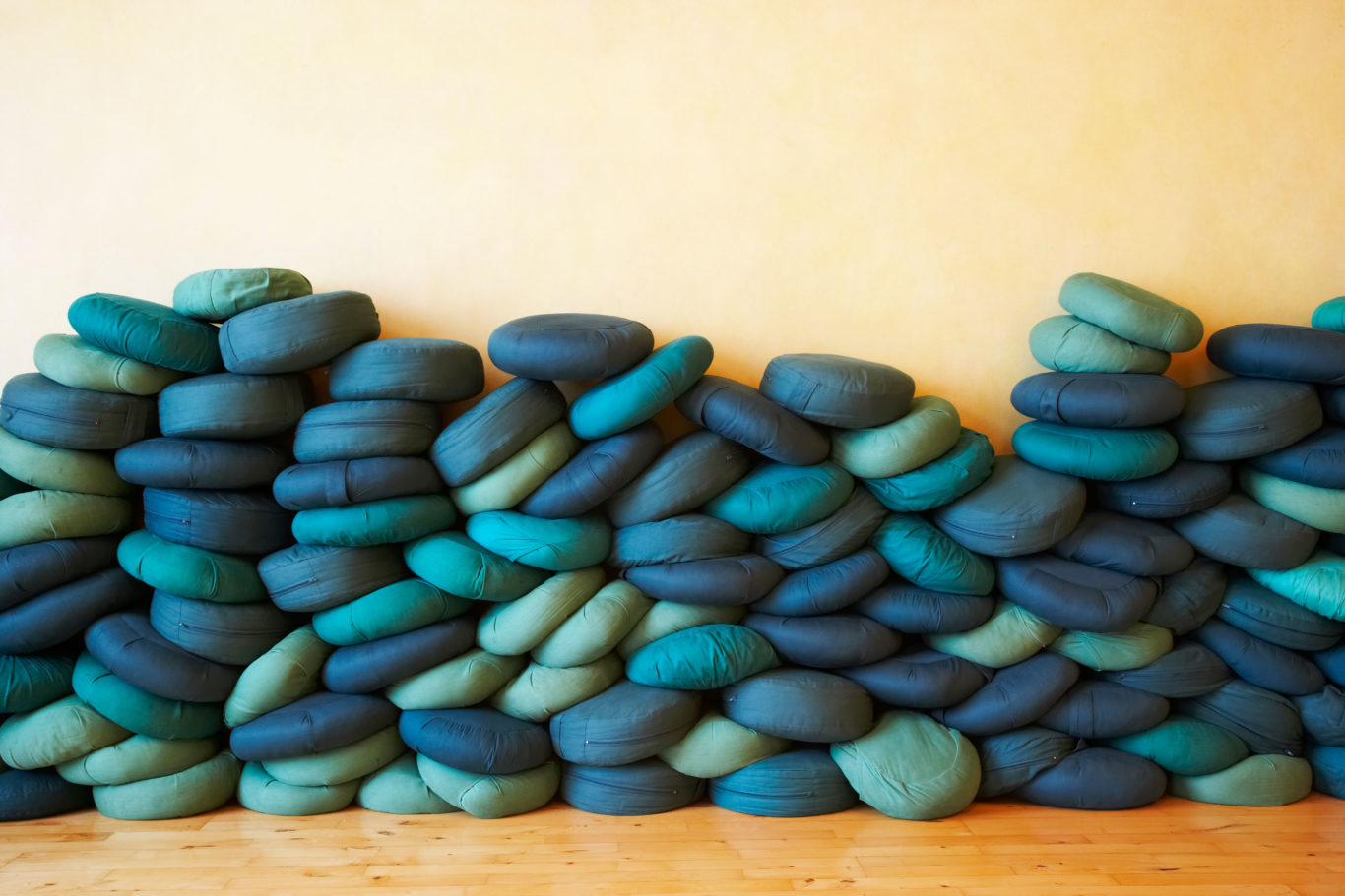 buddhist meditation cushions stacked against a wall