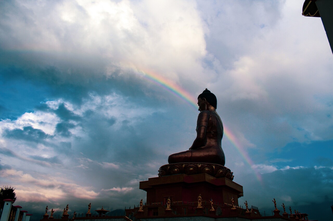 a Buddha statue illuminated by a rainbow, representing nirvana or enlightenment
