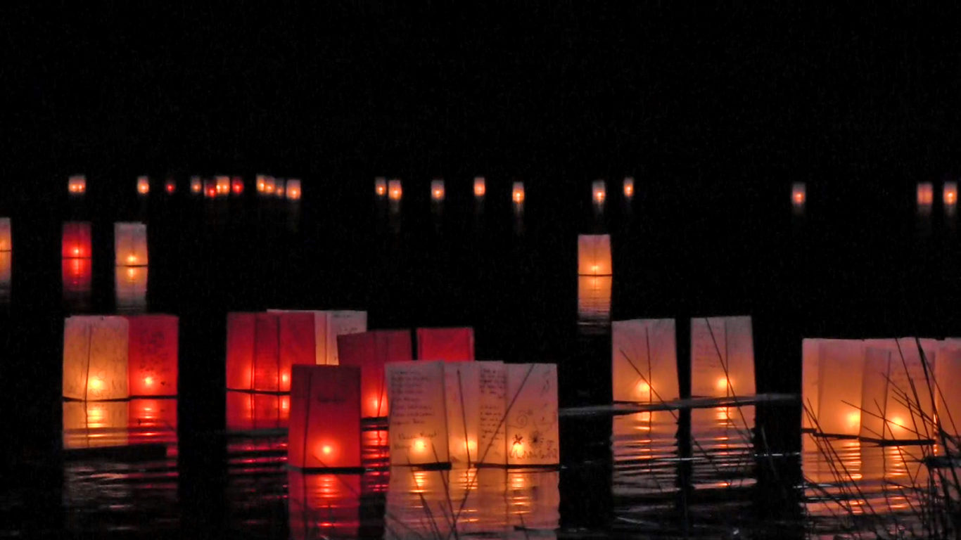 photograph of obon lanterns on a lake at night