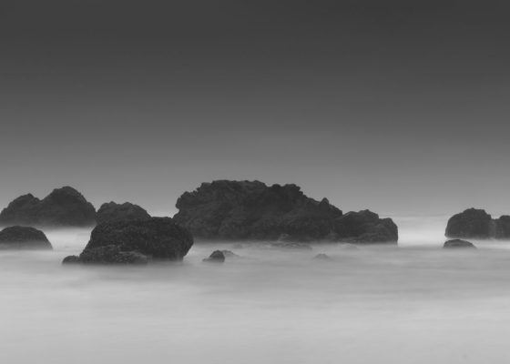 black and white photo of rocks in the ocean for story on the purpose of grief