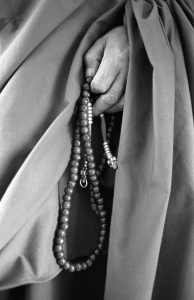 Hand holding mala beads; mala bead history