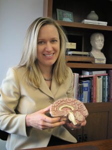 Neurologist Katrina Firlik smiling and holding a model of a brain.