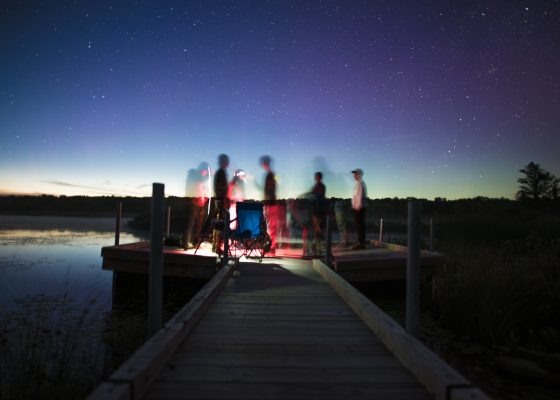 group of people having a nighttime gathering on a dock under starts for story about mind training