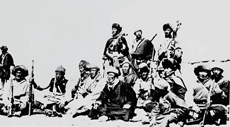 Surrounded by personal guards armed with submachine guns and bayonets, the Dalai Lama (sixth from left, seated)rests high in the Himalayas after fleeing Lhasa on March 17, 1959.