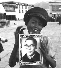 Image 2: A Tibetan street child in Lhasa with a photograph of the Dalai Lama. Courtesy Fosco Maraini.