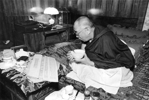 The Dalai Lama eating breakfast while preparing himself at Tawang Monastery for a teaching session; Arunachal Pradesh, India, May 8, 2003.