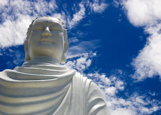 giant buddha against blue sky and clouds