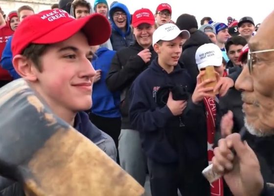 boy wearing MAGA hat confronting Native American elder for story on blame and buddhism