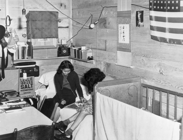 Japanese American Buddhists in an internment camp bedroom with Buddha image and American flag