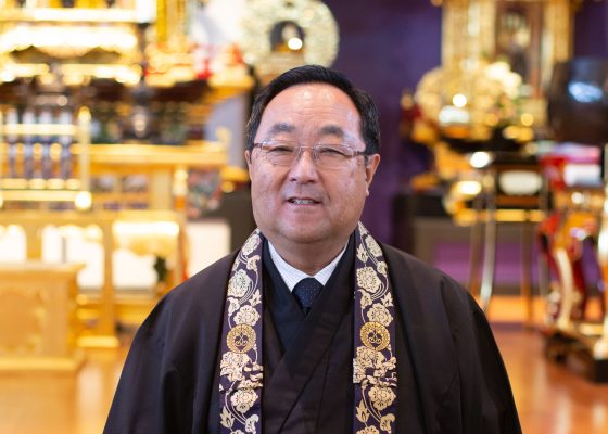 photograph of reverend marvin harada in front of shin buddhist shrine