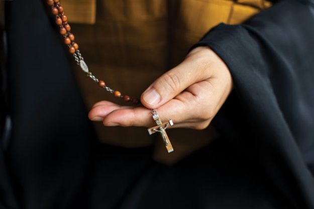 nun who converted from catholicism to zen holds a catholic rosary in her hand